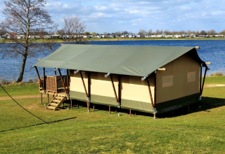 Safari-telt med sanitære faciliteter ved søbredden i Recreatiepark Riverside, Holland, på en solrig dag.