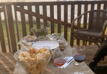 Udendørs spisebord med vin, brød og snacks på terrasse i Safari-telt ved søen i Riverside, Holland.