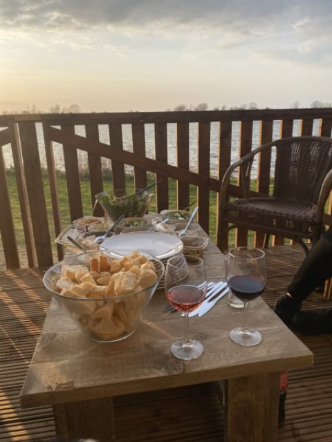 Abendessen im Freien mit Wein, Brot und Snacks auf einer Terrasse im Safari-Zelt am Riverside, Niederlande.