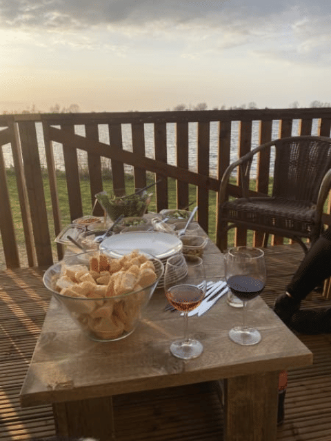 Udendørs spisebord med vin, brød og snacks på terrasse i Safari-telt ved søen i Riverside, Holland.