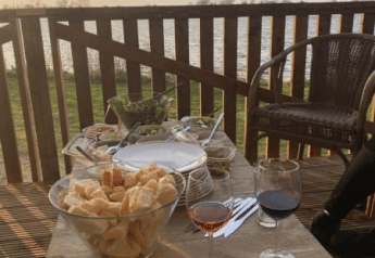 Outdoor table with wine, bread, and snacks on a terrace at a safari tent at Riverside in the Netherlands.