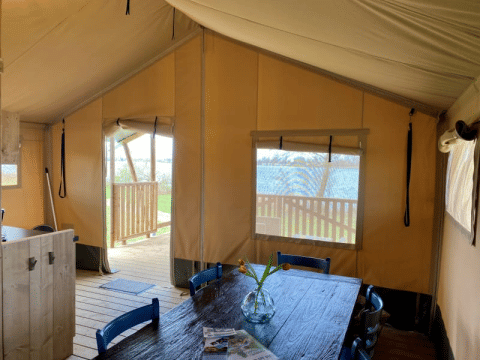 Intérieur de la tente Safari tent + sanitary au Recreatiepark Riverside, Pays-Bas, avec table à manger.