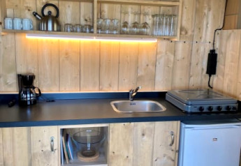 Træbeklædt tekøkken i Safari tent + sanitary ved Recreatiepark Riverside, Holland, med komfur og køleskab.
