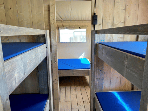 Innenansicht eines Safari-Zeltes mit Etagenbetten und Einzelbett im Recreatiepark Riverside, Niederlande.