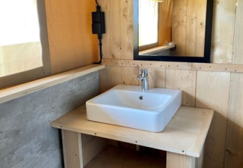 Lavandino con specchio e pareti in legno in una tenda safari al Recreatiepark Riverside, Paesi Bassi.