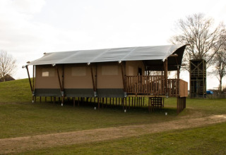 Tenda safari con servizi igienici su palafitte al Recreatiepark Riverside nei Paesi Bassi, su prato verde.