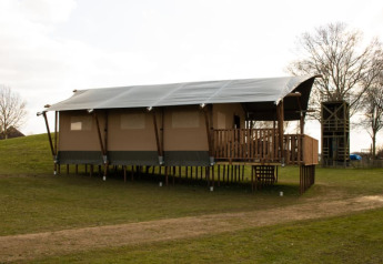 Tenda safari con servizi igienici su palafitte al Recreatiepark Riverside nei Paesi Bassi, su prato verde.