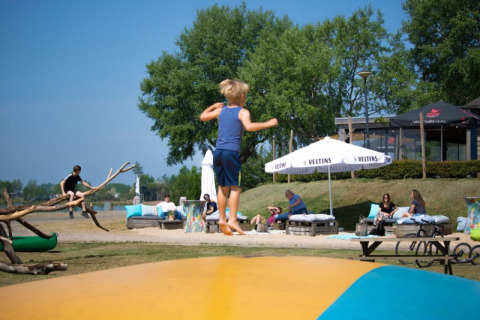 Kinder spielen auf einem Hüpfkissen am Safari-Zelt mit Sanitäranlagen im Recreatiepark Riverside, Niederlande.