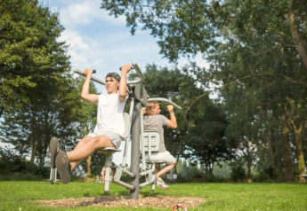 To personer træner på udendørs fitnessfaciliteter ved Safari-telt med sanitære forhold i Recreatiepark Riverside, Holland.
