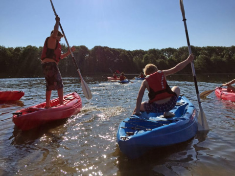 Niños con chalecos salvavidas reman y juegan en kayaks en un lago del Recreatiepark Riverside, Países Bajos.