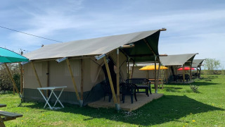 Safari-telte på Minicamping Sous les Cloches i Frankrig med farverige parasoller og grøn græsplæne.