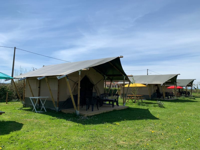 Safaritenten op Minicamping Sous les Cloches in Frankrijk met zitplekken buiten op groen grasveld.