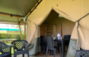 Safari-Zelt mit Sitzbereich und Gartenmöbeln bei Minicamping Sous les Cloches in Frankreich.