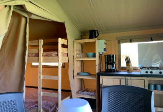Intérieur d'une tente safari au Minicamping Sous les Cloches, France, avec cuisine et lits superposés.