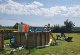 Billede af en forhøjet pool med badegæster på en grøn campingplads ved Safari tent på Minicamping Sous les Cloches, Frankrig.