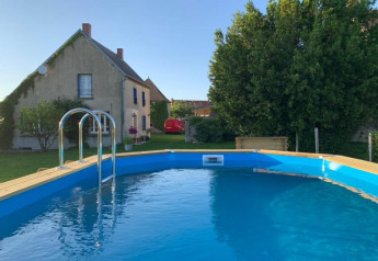 Piscina redonda elevada en jardín con casa de campo y árboles en Safari tent at Minicamping Sous les Cloches, Francia.