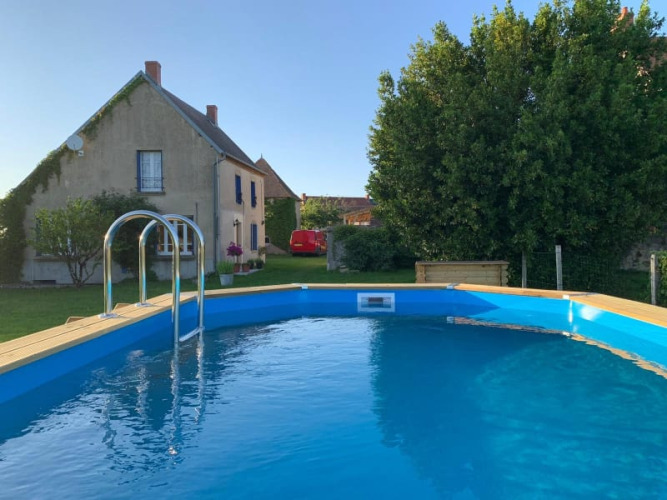 Ein runder Swimmingpool mit Leiter im Garten vor einem Landhaus bei Safari tent at Minicamping Sous les Cloches, Frankreich.