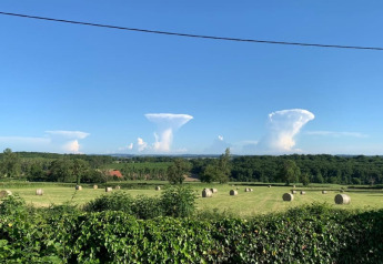 Vue sur des balles de foin et des nuages en forme de champignon à Safari tent au Minicamping Sous les Cloches en France.