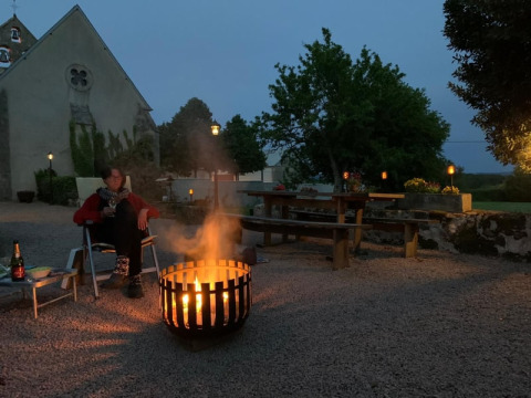Eine Person sitzt am Lagerfeuer vor dem Safari-Zelt auf Minicamping Sous les Cloches in Frankreich am Abend.