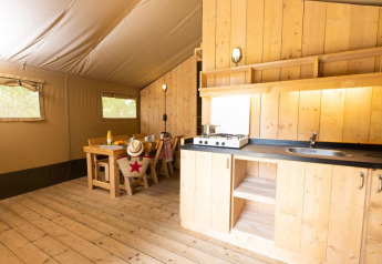 Interieur van een knusse safaritent met houten inrichting en keuken bij Le Camp de Florence, Frankrijk.