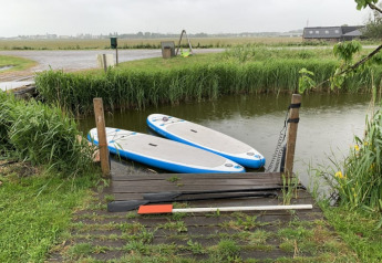 Due tavole da paddle vicino a un piccolo molo in legno presso Boerencamping Swarthoeve, Paesi Bassi.