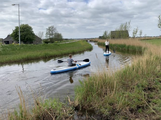 Deux personnes pagaient sur un petit cours d'eau près de Safari tent at Boerencamping Swarthoeve aux Pays-Bas.