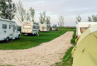 Safari tent and caravans at Boerencamping Swarthoeve in the Netherlands, parked on grassy areas and gravel road.
