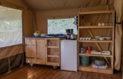 Coin cuisine d'une tente safari au Vakantiepark de Toffe Peer, Pays-Bas, avec étagères et réfrigérateur.