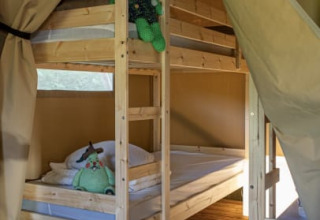 Interieur van een safaritent met stapelbedden bij Vakantiepark de Toffe Peer in Nederland.