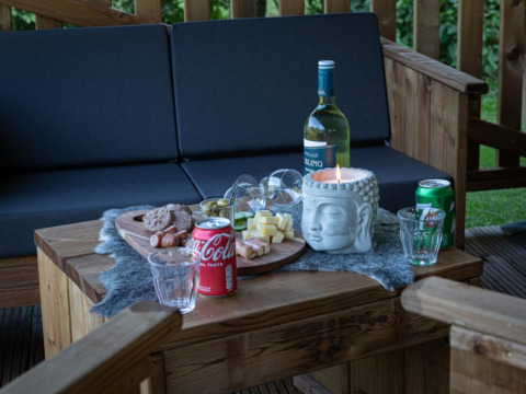 Zona de estar exterior en tienda safari de Vakantiepark de Toffe Peer, Países Bajos, con aperitivos y bebidas.