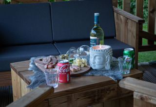 Zona de estar exterior en tienda safari de Vakantiepark de Toffe Peer, Países Bajos, con aperitivos y bebidas.