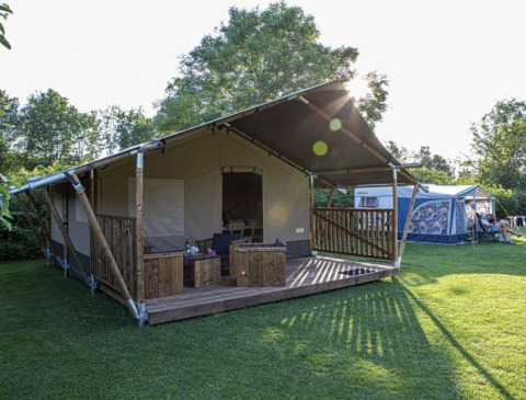 Tenda safari al Vakantiepark de Toffe Peer nei Paesi Bassi, veranda in legno e prato verde.
