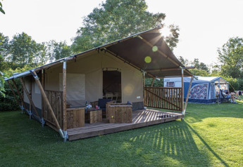 Tenda safari al Vakantiepark de Toffe Peer nei Paesi Bassi, veranda in legno e prato verde.