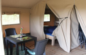 Innenansicht eines Safari-Zeltes auf Camping de Waterbuffelfarm in den Niederlanden mit Tisch und Bett.