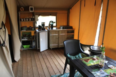 Interno di una tenda safari con angolo cottura e tavolo da pranzo al Camping de Waterbuffelfarm, Olanda.