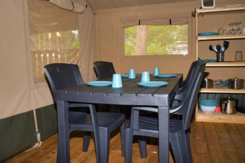 Interieur van safaritent met zwarte tafel, vier stoelen en blauw servies op Camping Aller-Leine-Tal, Duitsland.