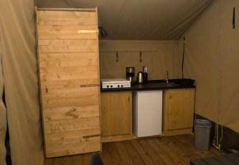 Innenaufnahme eines Safari-Zeltes mit Küchenzeile und Holztür auf dem Camping Aller-Leine-Tal in Deutschland.