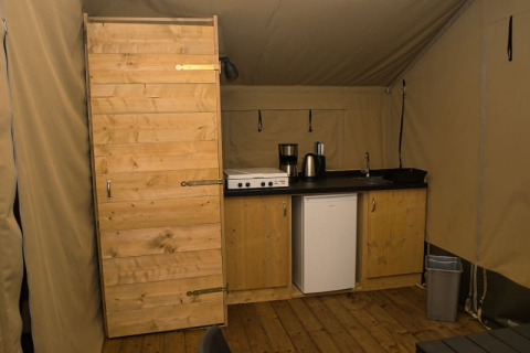 Interieur van een safaritent met kitchenette en houten deur bij Camping Aller-Leine-Tal in Duitsland.