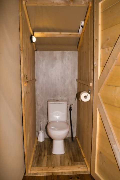Toilette in einem Safarizelt auf dem Campingplatz Aller-Leine-Tal in Deutschland mit Holzwänden.