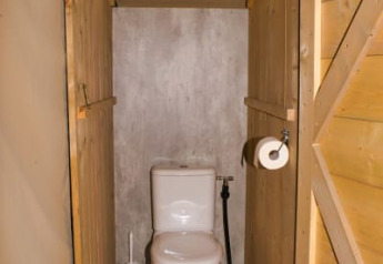 Toilet inside a safari tent at Camping Aller-Leine-Tal in Germany, featuring wooden walls and flooring.