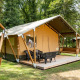 Safari telt med terrasse og stole i en grøn skovcamping, ideel til glamping og naturoplevelser.