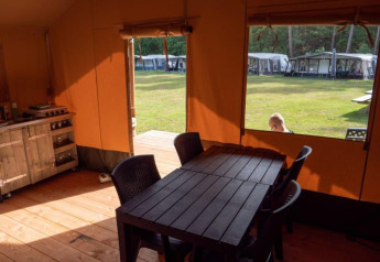 Vista interna di tenda safari con tavolo da pranzo al Recreatiepark de Wrange, Paesi Bassi, vista sull’esterno.