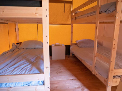 Binnenkant van een safaritent met stapelbedden en houten vloer bij Recreatiepark de Wrange, Nederland.