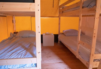 Chambre d'une tente safari au Recreatiepark de Wrange aux Pays-Bas, avec lits superposés et sol en bois.