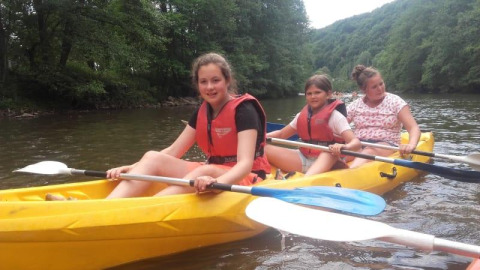 Tres niñas remando en un kayak amarillo en el río cerca de Safari tent en Camping Village Sy, Bélgica.