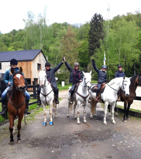 Fünf Reiter posieren auf Pferden vor einem Safari-Zelt im Camping Village Sy, Belgien, umgeben von Wald.