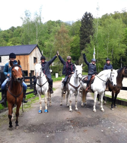 Vijf personen te paard voor een safaritent bij Camping Village Sy in België, omringd door groene bomen.