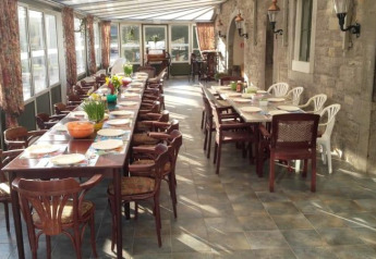 Mesa larga preparada para muchos comensales en un espacio luminoso de la tienda safari en Camping Village Sy, Bélgica.
