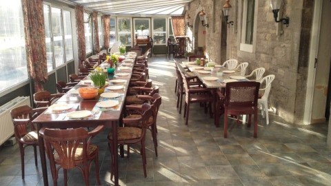 Langer gedeckter Tisch in einem hellen, geräumigen Essbereich im Safari-Zelt von Camping Village Sy, Belgien.