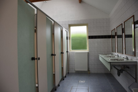 Offentligt badeværelse med kabiner, håndvaske og spejle i Safari-teltet på Camping Village Sy, Belgien.
